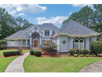 Stunning home featuring a manicured lawn, inviting walkway, and a unique architectural design with arched windows and a stately entrance at 1213 Grande Vw, Loganville, GA 30052