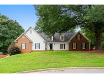 Charming two-story home with a well-manicured front yard, brick accents, and mature trees at 1732 Winding Woods Ln, Jonesboro, GA 30236