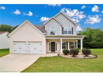 Charming two-story home featuring a two-car garage, landscaped yard, and inviting front porch under a bright blue sky at 176 Windy Cir, Mcdonough, GA 30253