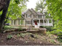 Beautiful two-story home with a welcoming front porch and well-maintained landscaping and a red front door at 1170 Spring Oak Way, Cumming, GA 30041