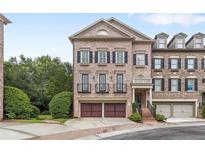 Beautiful brick townhome featuring a two-car garage, black shutters, and manicured landscaping at 2291 Falmouth Se Ct # 23, Smyrna, GA 30080