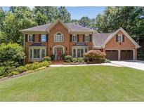 Beautiful two-story brick home with mature trees, manicured lawn and three-car garage at 1835 Redbourne Dr, Atlanta, GA 30350