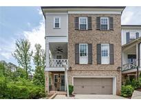 Charming two-story townhouse with brick facade, shutters, and an attached garage at 385 Rowes Cir, Alpharetta, GA 30009