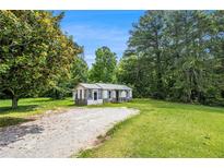 View of cozy home on large lot with gravel driveway and lush green lawn at 1186 Eastview Ne Rd, Conyers, GA 30012