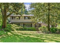 Traditional home with large trees, lush green grass, and manicured shrubs in a quiet neighborhood at 2839 Orion Dr, Decatur, GA 30033