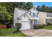 Charming two-story home with white stucco, attached garage, blue shutters, and manicured landscaping at 2894 Regent Walk Dr, Duluth, GA 30096