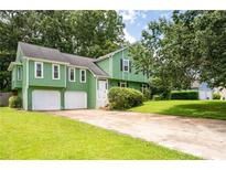 Charming green home with a two-car garage and a well-manicured lawn at 936 Tyrell Dr, Austell, GA 30106