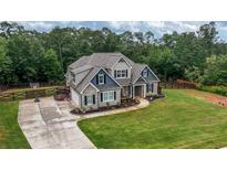 Charming two-story home with a lush green lawn, fenced yard, and long concrete driveway at 7532 Milford Pl, Douglasville, GA 30135