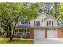 Charming two-story home with a brick garage, light siding, a porch, and a beautifully landscaped front yard at 3614 Spring Leaf Ln, Acworth, GA 30101
