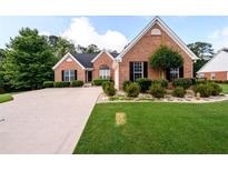 Charming brick home with a well-manicured lawn, complemented by mature trees and a paved driveway at 7090 Valley Landing Ct, Cumming, GA 30041