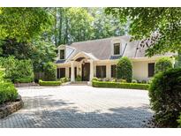 Charming brick home features an inviting covered entryway, a brick driveway and mature landscaping at 1016 Old Powers Ferry Rd, Atlanta, GA 30327