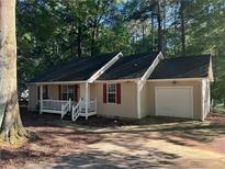 Charming single-story home featuring a front porch, red shutters, and an attached garage, nestled among mature trees at 796 Cohran Store Rd, Douglasville, GA 30134