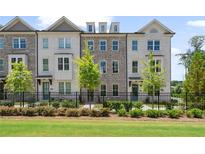 Attractive townhome exterior with white-painted brick, black fence and well-manicured landscaping at 102 Brackley Dr, Cumming, GA 30040