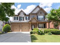 Charming two-story brick home featuring a two-car garage, landscaped yard, and covered front porch at 812 Autry Oak Ct, Alpharetta, GA 30022