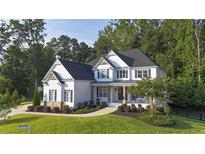 Charming two-story home with a landscaped yard, inviting front porch, and classic white and blue color scheme at 1895 Henley Way, Alpharetta, GA 30009