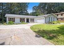 Charming single-story home with painted brick, a well-manicured lawn, and an attached two-car garage at 3321 Georgian Woods Cir, Decatur, GA 30034