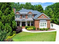 Beautiful brick home featuring mature landscaping and a welcoming front porch at 141 Olde Heritage Way, Woodstock, GA 30188