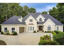 Elegant home featuring a well-manicured lawn, mature trees and a driveway leading to an attached garage at 2885 Coles Way, Atlanta, GA 30350