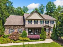 Charming two-story home featuring a stone facade, landscaped yard, and inviting front porch with rocking chairs at 1344 Hamilton Creek Nw Dr, Kennesaw, GA 30152