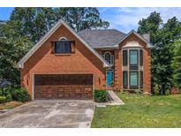 Charming two-story brick home with a well-manicured lawn and a quaint blue front door at 1452 Crooked Tree Cir, Stone Mountain, GA 30088