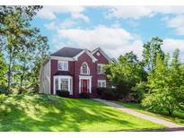Charming brick two-story home with a red front door, lush lawn, and mature trees at 1100 Midland Way, Lawrenceville, GA 30043