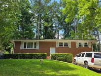 Charming brick ranch-style home with lush front lawn and manicured hedges, plus a white SUV parked on the side at 3293 Oakcliff Rd, Doraville, GA 30340