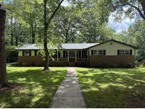 Charming single-story brick home with mature trees and a stone walkway at 420 Creekview Ct, Marietta, GA 30064