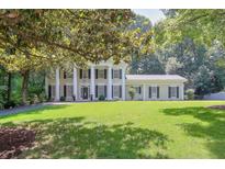 Stately two-story home with columns, black shutters, green lawn, and mature shade trees at 575 Valley Hall Dr, Sandy Springs, GA 30350