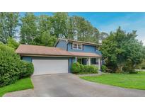 Charming blue home featuring a well-maintained front lawn, mature trees, and a two-car garage at 2142 Troutdale Dr, Decatur, GA 30032