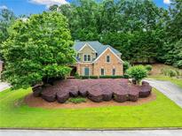 Beautiful brick home featuring an expansive green lawn, mature landscaping, and a circular driveway at 205 Camden Creek Ct, Lawrenceville, GA 30043