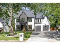 Striking two-story home with a modern design, gray roof, dark trim, an inviting driveway, and lush landscaping at 2297 Nesbitt Ne Dr, Brookhaven, GA 30319