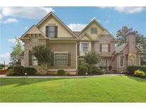 Charming two-story home with manicured lawn, brick and stone exterior, and professionally landscaped front yard at 3099 Hidden Falls Dr, Buford, GA 30519