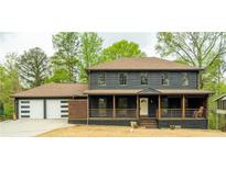 Charming two-story home featuring a front porch, two-car garage, neutral paint, and mature trees at 5254 Greenpoint Drive, Stone Mountain, GA 30088