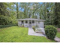 Charming one-story home with a welcoming front yard and walkway, surrounded by mature trees and green foliage at 86 Stratford Nw Dr, Atlanta, GA 30311