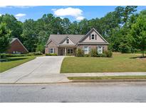 Charming single-Gathering home with brick facade, manicured lawn, and a paved driveway leading to a cozy entrance at 902 Edgewater Dr, Loganville, GA 30052