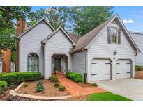 Charming two-story home with landscaped yard, brick walkway, attached two-car garage, and light gray shingle siding at 1605 Spinnaker Drive, Alpharetta, GA 30005