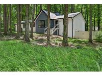 View of two-story home with mixed siding, surrounded by mature trees and lush greenery at 5077 Martindale Ln, Stone Mountain, GA 30088