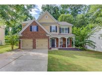Charming two-story home features a brick and tan exterior, a well-manicured lawn, and a two-car garage at 4092 Duran Ln, Auburn, GA 30011