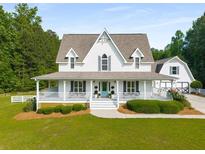 Charming white two-story home featuring a large porch, manicured lawn, and lush landscaping at 692 Brooks Woolsey Rd, Brooks, GA 30205