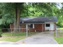 Modest brick home with a lawn, driveway, and mature trees, providing a classic curb appeal at 8469 Shiloh Ct, Jonesboro, GA 30238