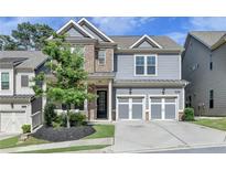 Beautiful two-story home with gray siding, brick accents, a manicured lawn, and an attached two-car garage at 1045 Penny Ln, Roswell, GA 30076