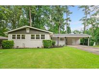 Charming single-story home featuring a brick facade, well-manicured lawn, and a covered carport, nestled in a lush, green landscape at 3222 Edgemont Way, Decatur, GA 30032