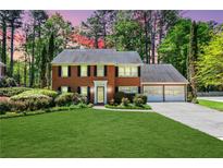 Charming brick home with a well-manicured lawn, mature trees, and an attached two-car garage at 2830 Scottish Mill Way, Marietta, GA 30068