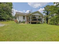 Charming home with a welcoming front porch and lush green lawn, perfect for outdoor living at 3411 Morgan Rd, Canton, GA 30115