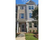 Charming townhome featuring a brick facade, gray accents, and manicured landscaping at 545 Fundao Ln # 25, Lawrenceville, GA 30046