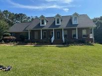 Charming brick home with a columned front porch and dormer windows, set on a large lawn under a bright sky at 705 S Bethany Rd, Mcdonough, GA 30252