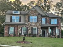 Beautiful two-story home with a combination of brick and stone facade, complemented by dark shutters and a well-maintained lawn at 2304 Northglenn Ct, Conyers, GA 30013