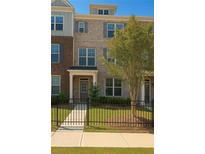 Charming three-story townhome featuring a brick facade, a well-manicured lawn, and a black metal fence at 559 Fundao Ln # 21, Lawrenceville, GA 30046