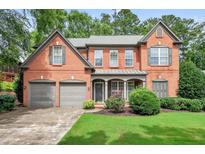 Charming two-story brick home with a well-manicured lawn and a two-car garage at 1065 Bookhout Drive Dr, Cumming, GA 30041