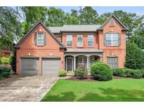 Charming two-story brick home featuring a well-maintained lawn, two-car garage, and inviting front porch at 1065 Bookhout Drive Dr, Cumming, GA 30041